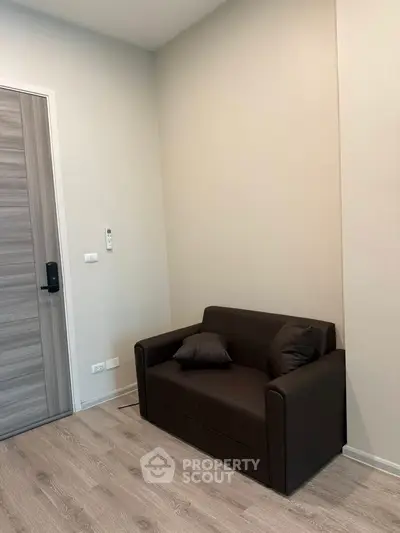 Cozy corner with a modern brown sofa and wooden door in a minimalist room.