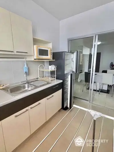 Modern kitchen with sleek cabinets, fridge, and microwave in a stylish apartment