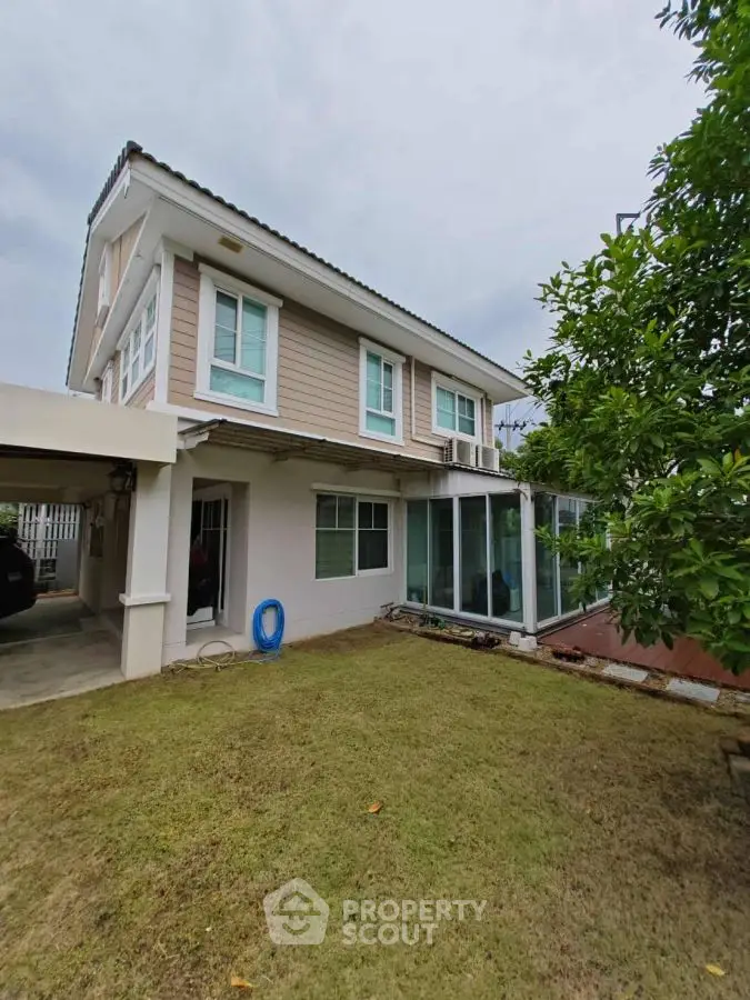 Charming two-story house with lush garden and spacious carport, perfect for family living.