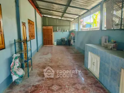 Spacious covered outdoor area with tiled flooring and storage space, perfect for versatile use.