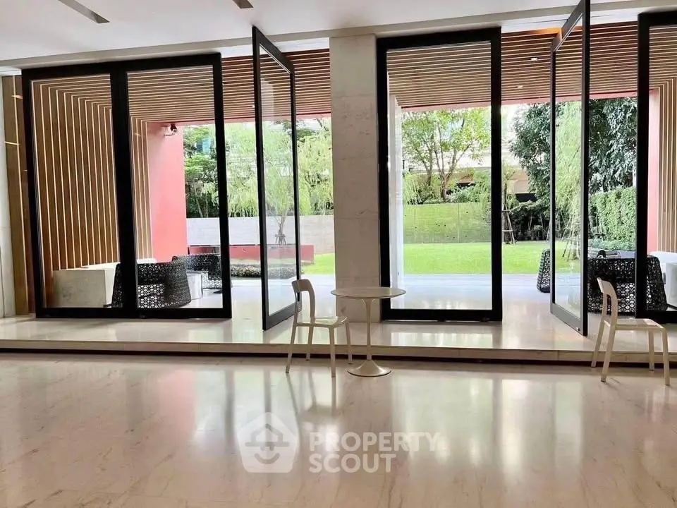 Elegant modern living space with large glass doors opening to a lush garden view.