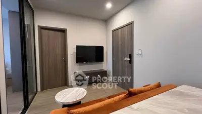Modern living room with sleek design and wall-mounted TV, featuring cozy orange sofa and stylish coffee table.