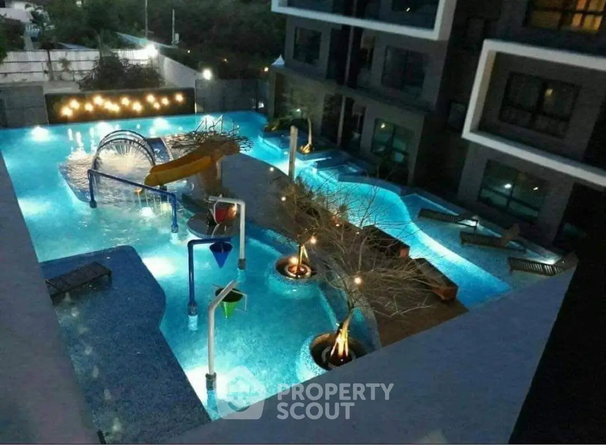 Luxurious apartment complex with illuminated pool and water features at night.