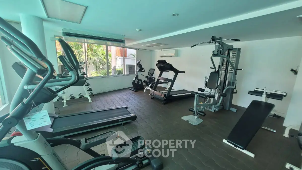 Spacious modern gym with state-of-the-art equipment and large windows for natural light.