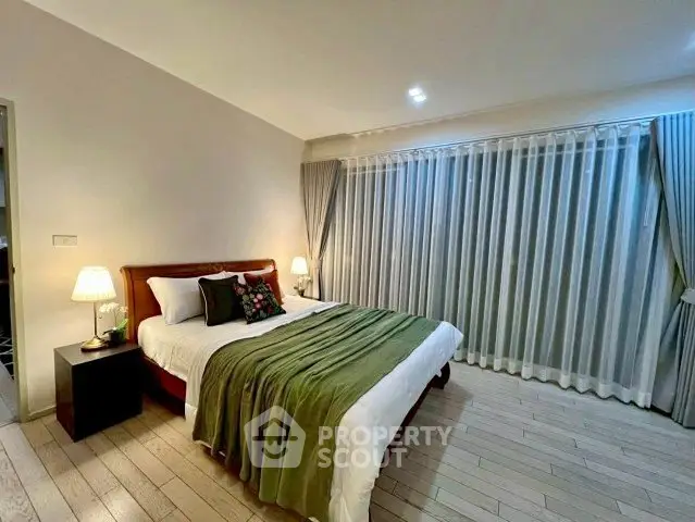 Spacious bedroom with elegant decor and large window drapes, perfect for relaxation.
