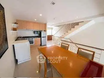 Modern kitchen with open layout and dining area, featuring sleek appliances and contemporary design.