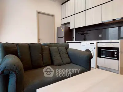 Modern living room with stylish kitchen, featuring a cozy sofa and built-in appliances for urban living.