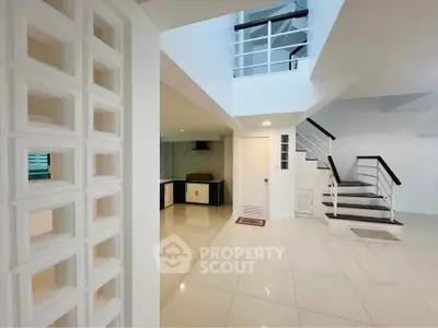Modern white interior with sleek staircase and open layout kitchen