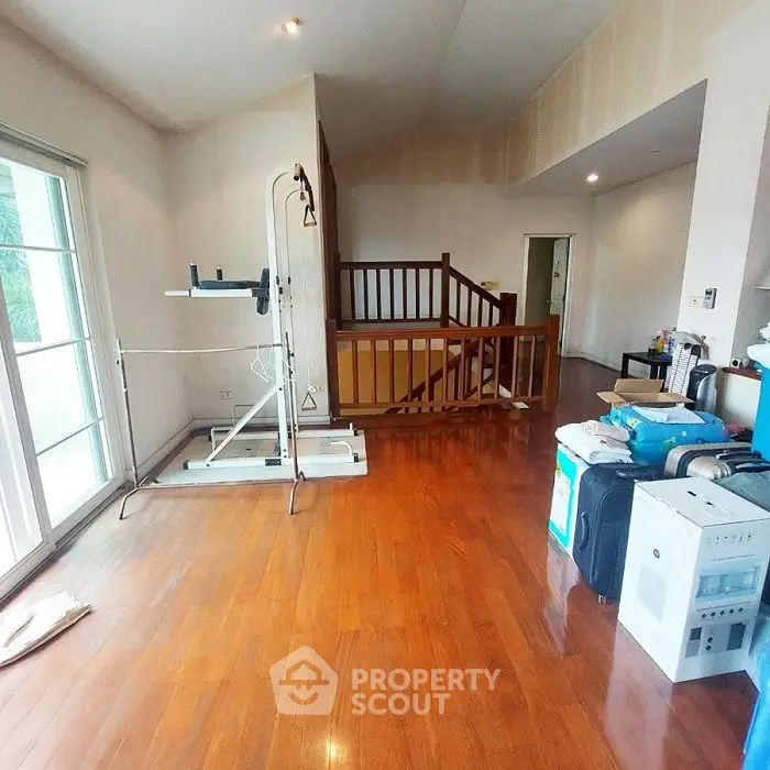 Spacious room with wooden flooring and exercise equipment, ideal for home gym setup.