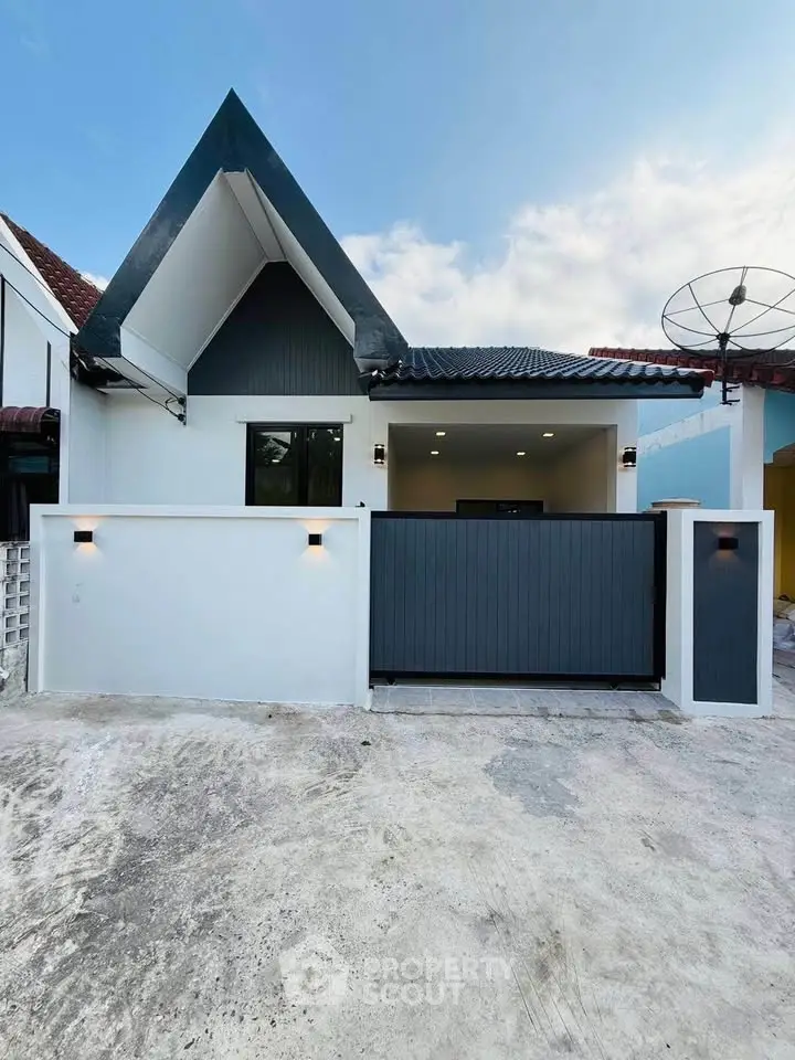 Charming modern house exterior with unique roof design and gated entrance, perfect for contemporary living.