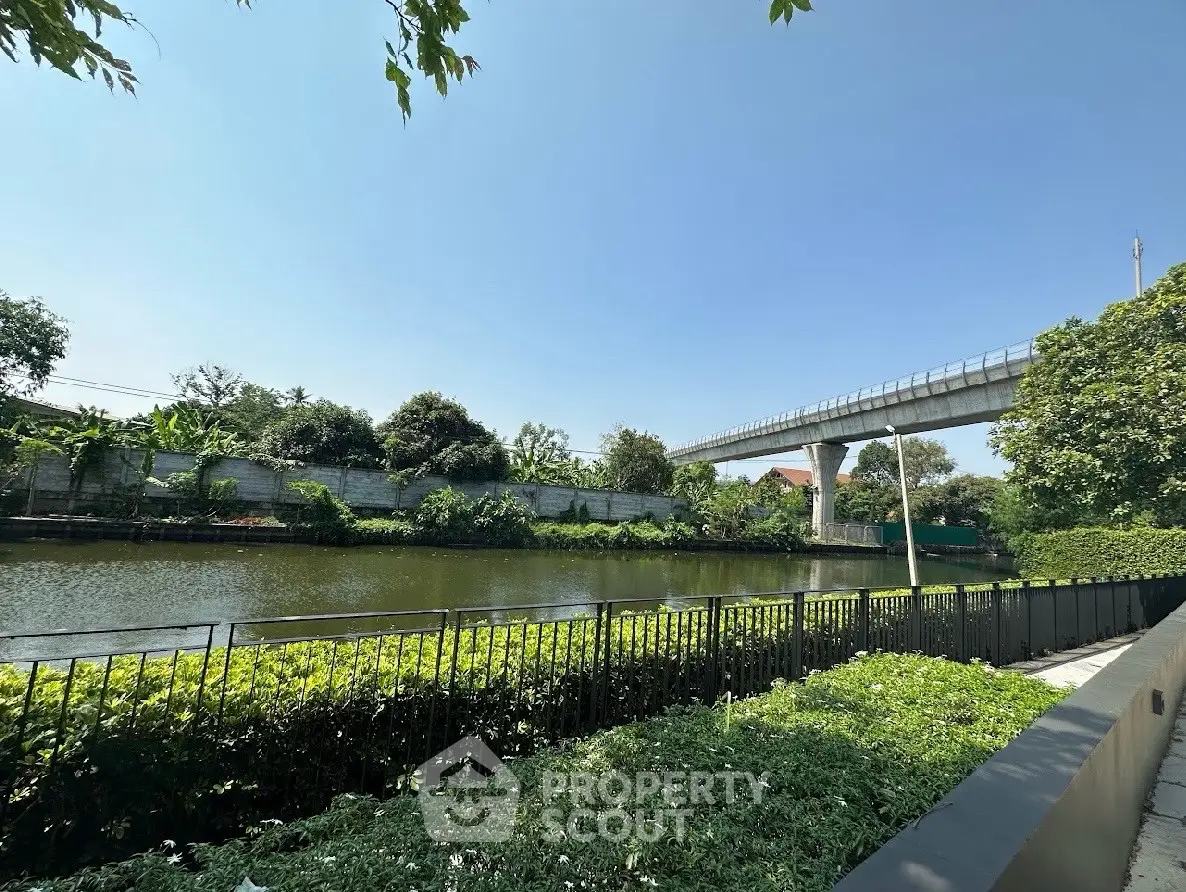 Scenic view of a serene river with lush greenery and a modern bridge, perfect for tranquil living.