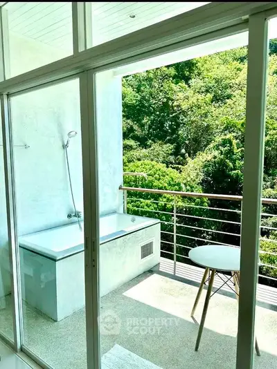 Luxurious balcony with outdoor bathtub and lush green view, perfect for relaxation and tranquility.