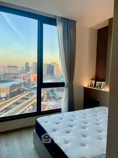 Modern bedroom with city view and large window, showcasing urban living.