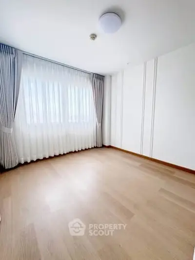 Spacious empty room with large window and elegant curtains, perfect for customization.