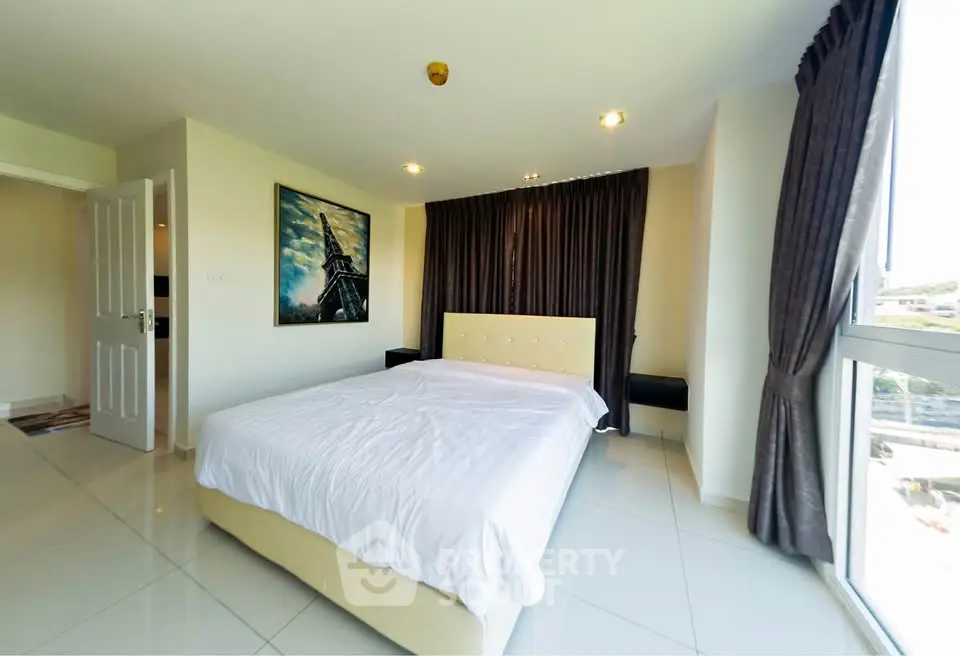 Spacious bedroom with modern decor and large windows offering ample natural light.
