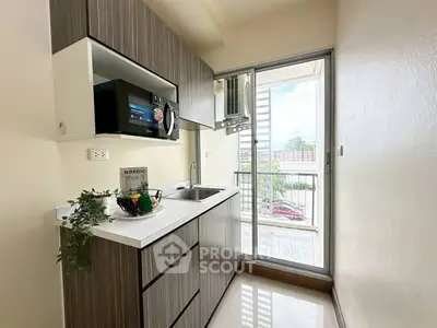 Modern kitchen with sleek cabinetry and balcony view in stylish apartment.