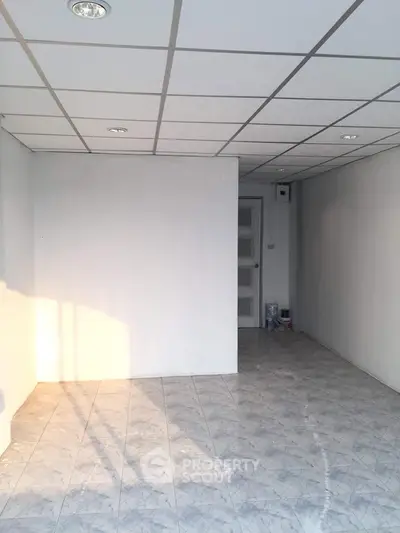 Spacious empty room with tiled floor and white walls, ideal for customization.