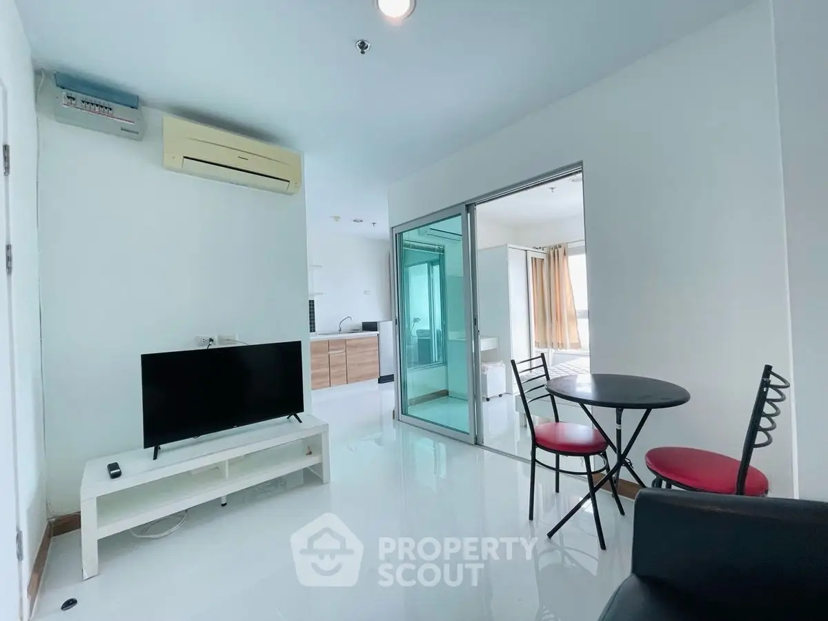 Modern living room with sleek design and open kitchen layout, featuring a TV and dining area.