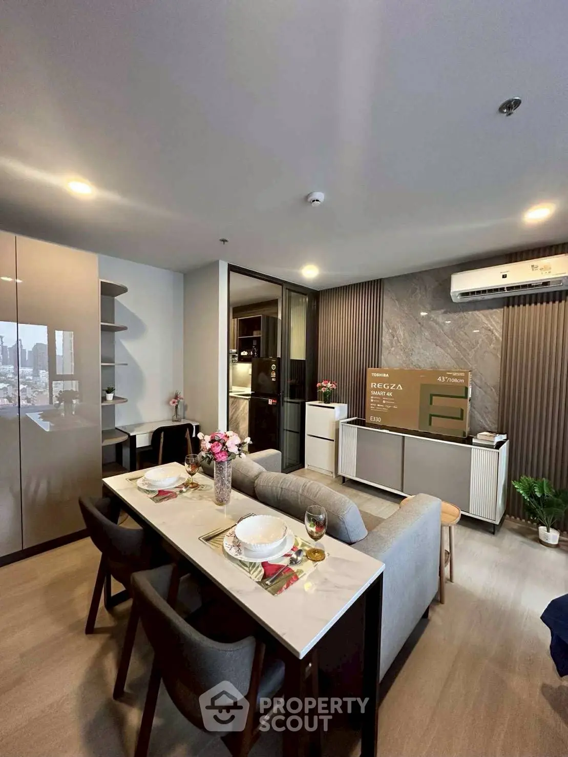 Modern living room with dining area and city view, featuring sleek furniture and stylish decor.