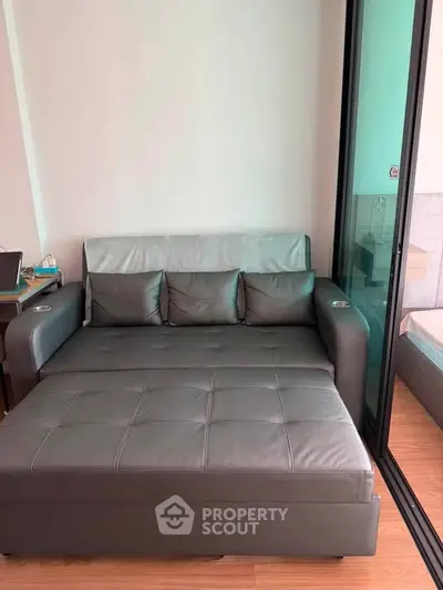 Modern living room with stylish gray sofa and glass partition, perfect for cozy relaxation.