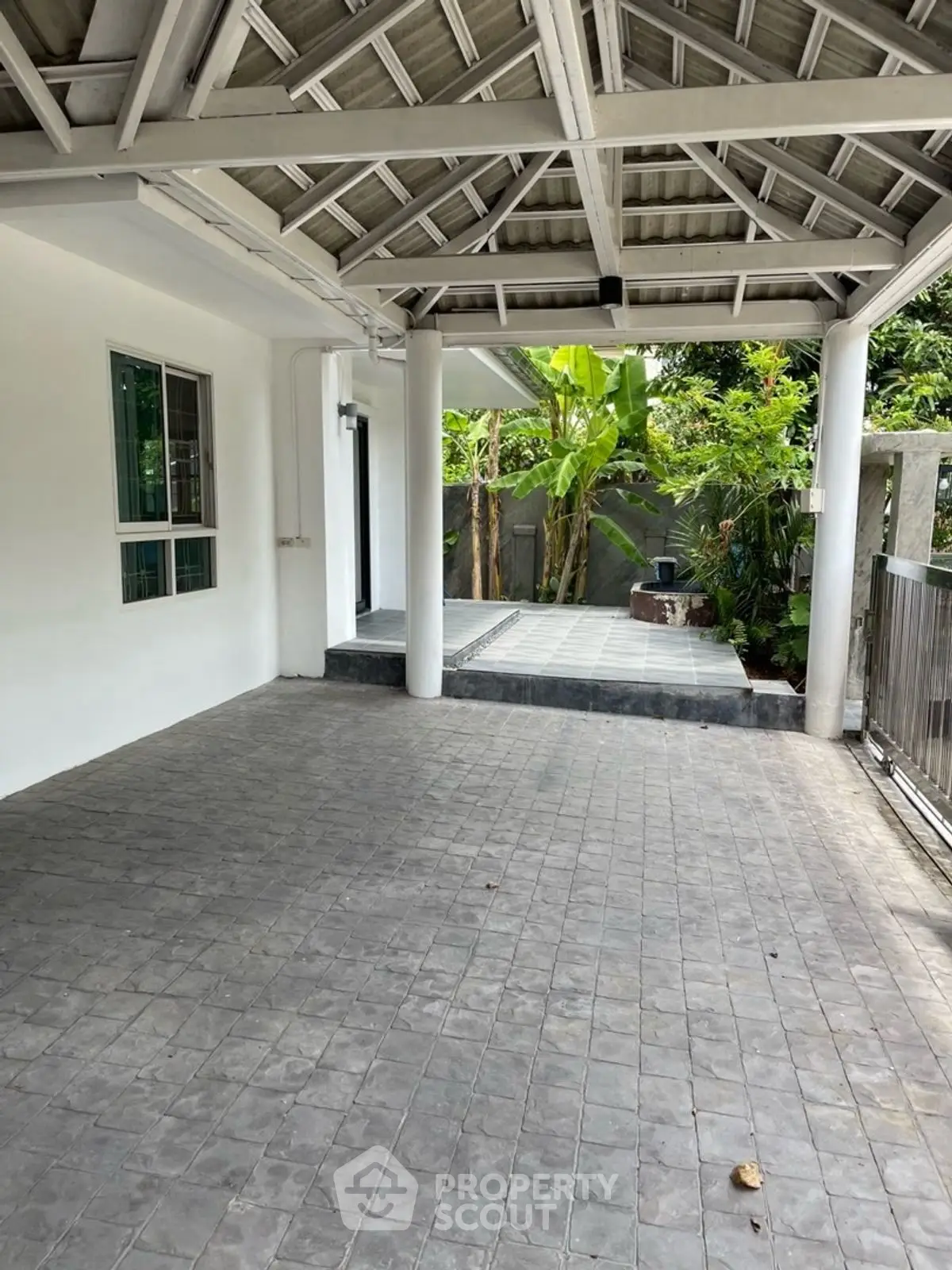 Charming outdoor patio with tiled flooring and lush greenery, perfect for relaxation and entertaining.