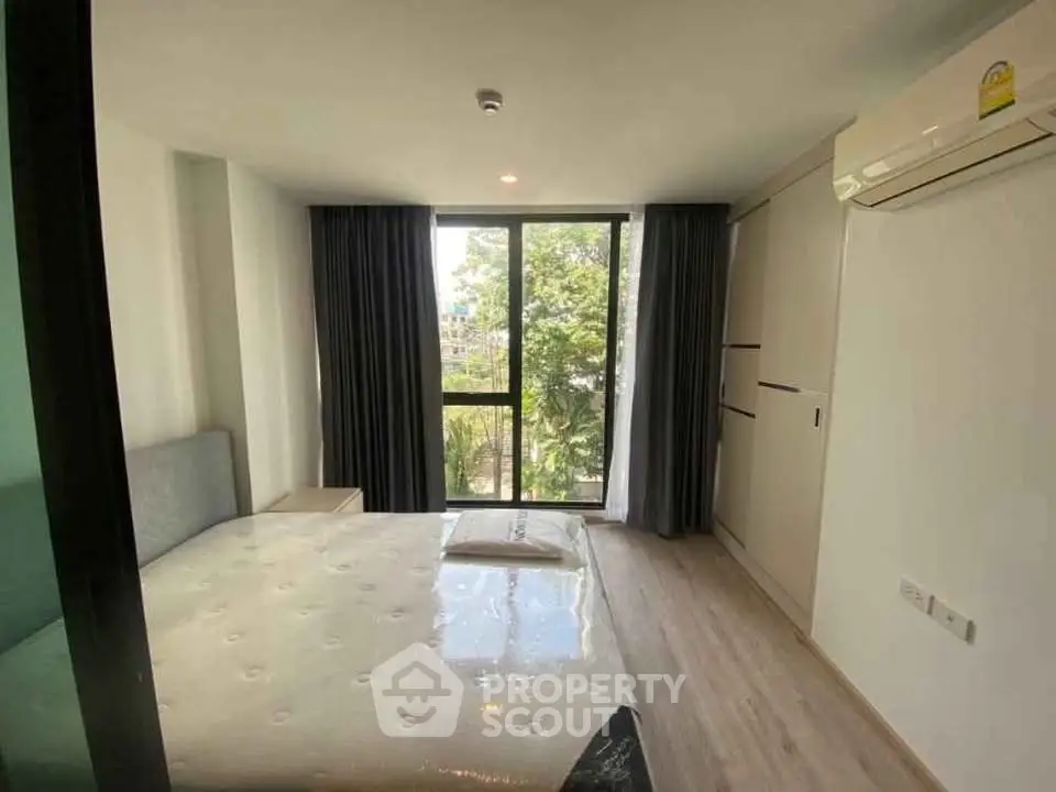 Modern bedroom with large window and air conditioning in a stylish apartment.