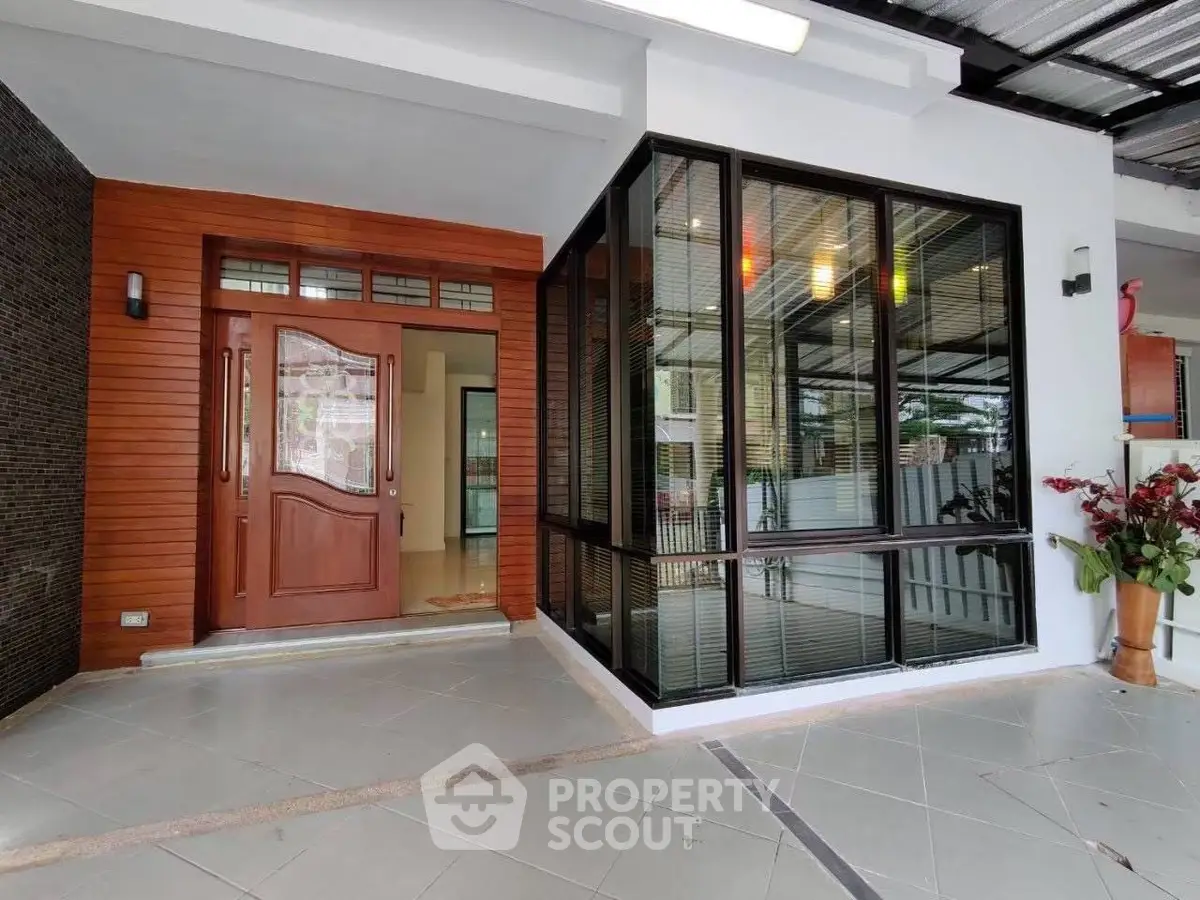 Modern home entrance with large windows and stylish wooden door