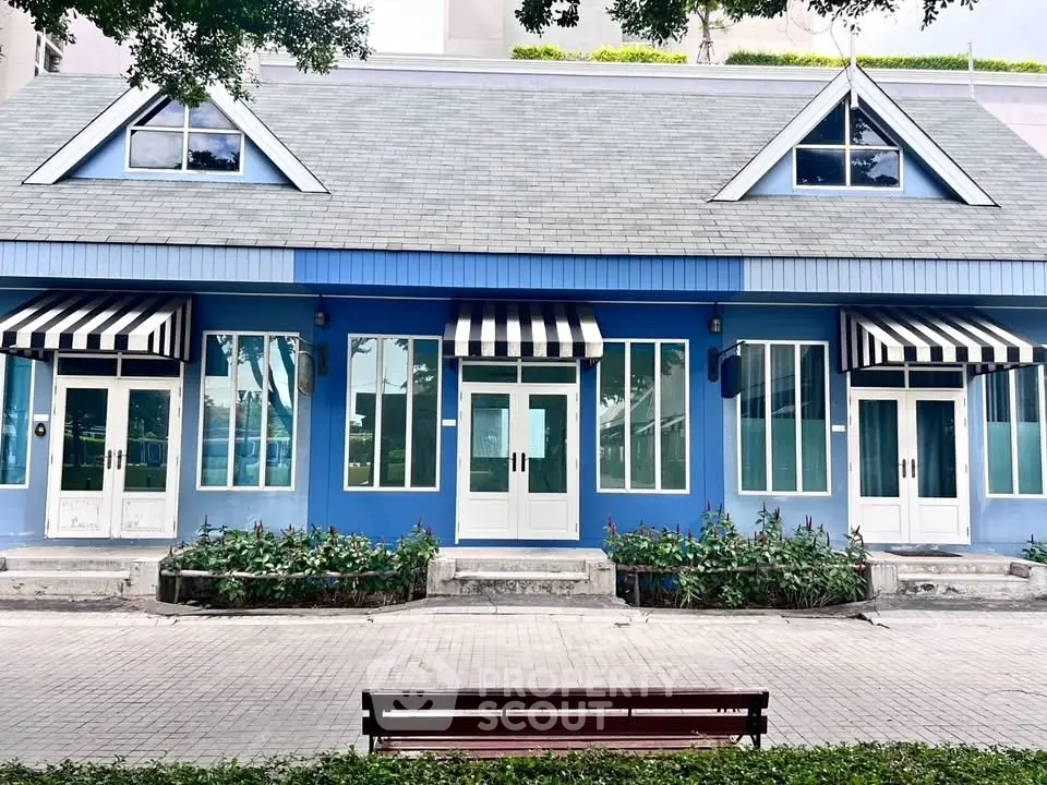 Charming blue building with striped awnings and lush landscaping