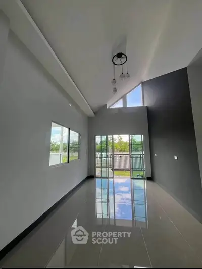 Spacious modern living room with high ceilings and large windows offering natural light and outdoor views.
