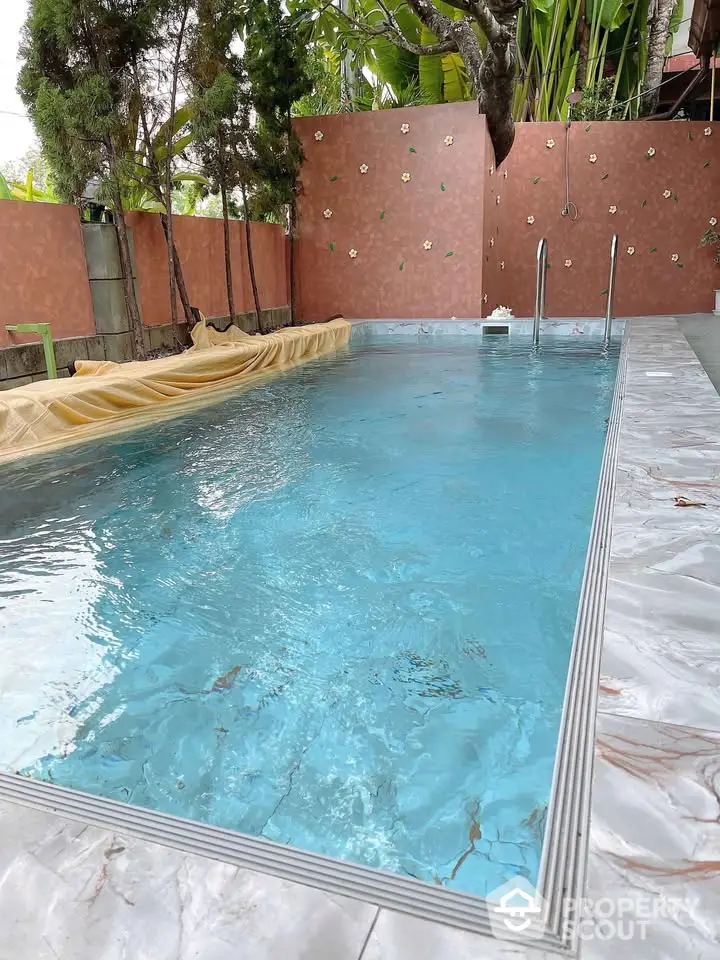 Luxurious private swimming pool with elegant marble tiles and lush greenery