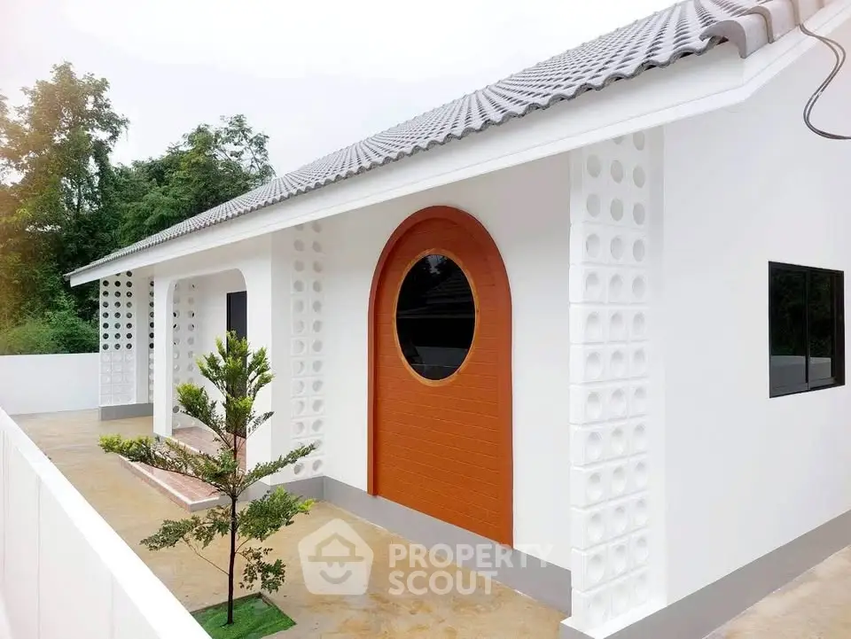 Modern white house with unique circular door and stylish exterior design.