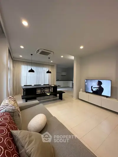 Modern open-plan living room with stylish decor and large TV