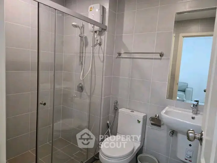Modern bathroom with glass shower enclosure and sleek fixtures in a contemporary apartment.