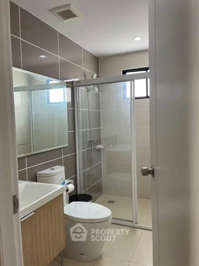 Modern bathroom with glass shower and sleek fixtures in contemporary home.