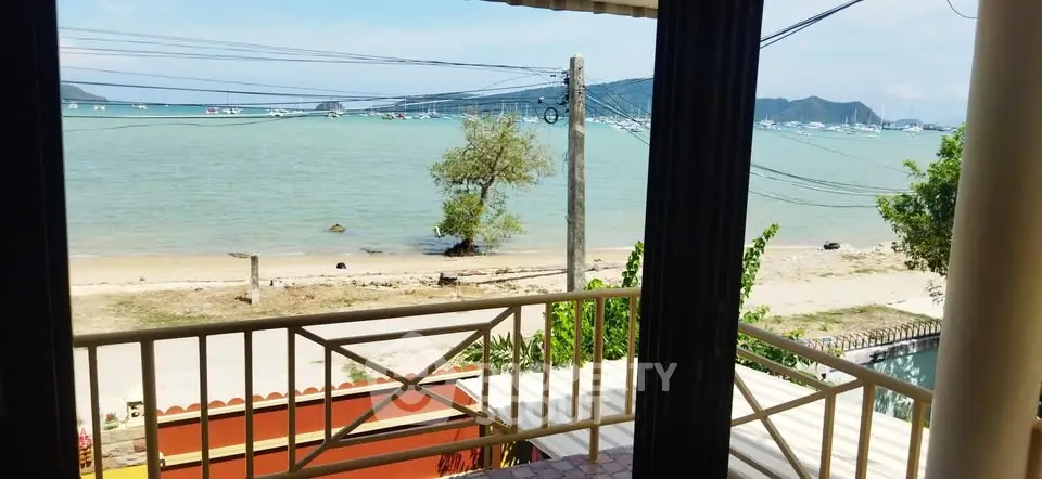 Stunning beachfront view from a balcony overlooking serene ocean and boats.