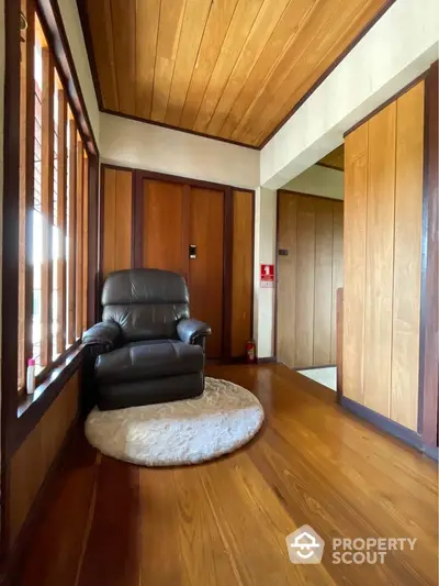 Cozy wooden interior with armchair and plush rug in a warm inviting corner.