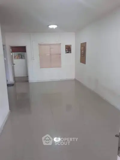 Spacious empty room with tiled flooring and neutral walls, ideal for customization.