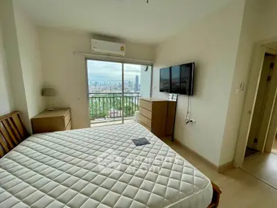 Spacious bedroom with city view and modern furnishings in high-rise apartment.