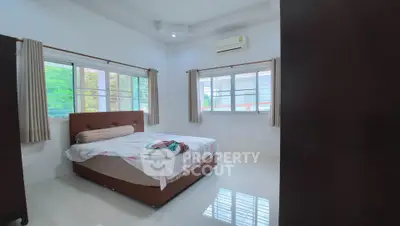 Spacious bedroom with large windows and air conditioning in modern home.