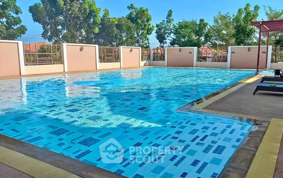 Luxurious outdoor swimming pool with clear blue water and surrounding greenery in a serene residential area.
