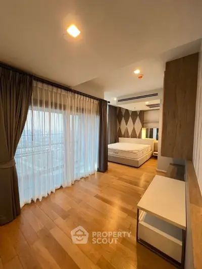 Spacious bedroom with large windows and elegant wooden flooring, offering a serene and modern living space.