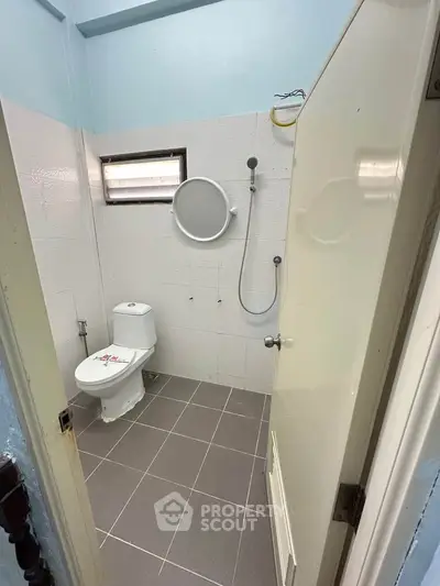 Compact bathroom with modern fixtures and tiled flooring, featuring a shower and toilet in a minimalist design.