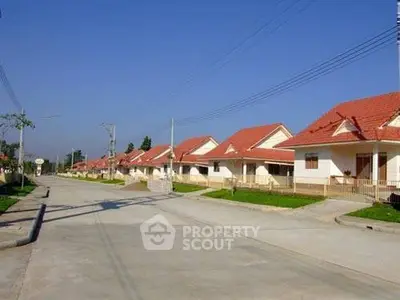 Charming suburban neighborhood with row of single-story houses and red roofs under clear blue sky.