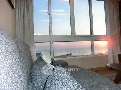 Stunning living room with panoramic ocean view through large windows at sunset.
