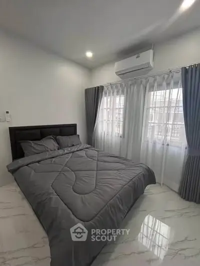 Modern bedroom with sleek design, featuring a cozy bed and large windows for natural light.
