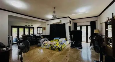 Spacious living room with open layout and modern decor, featuring large windows and elegant lighting.