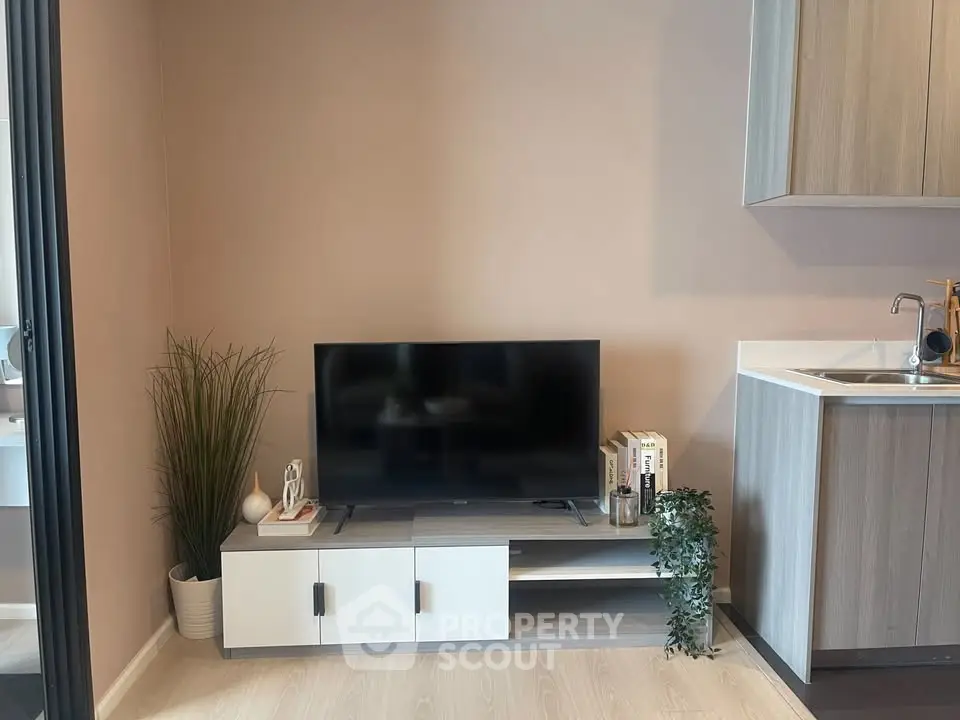 Modern living room with sleek TV stand and kitchenette, perfect for urban living.