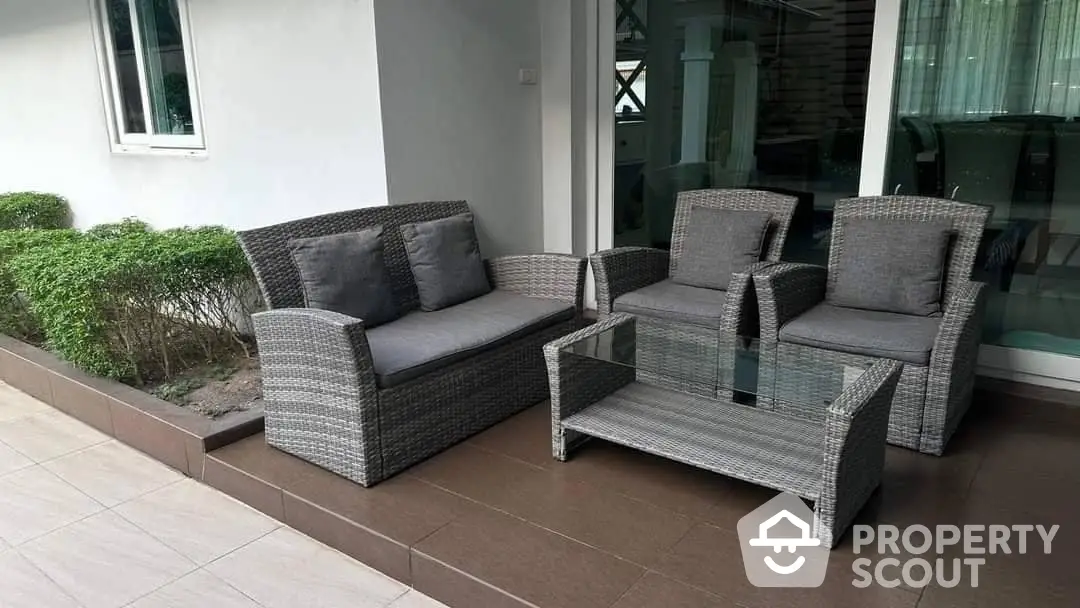 Inviting outdoor patio area with modern wicker furniture set, perfect for relaxation and entertaining in a serene home environment.