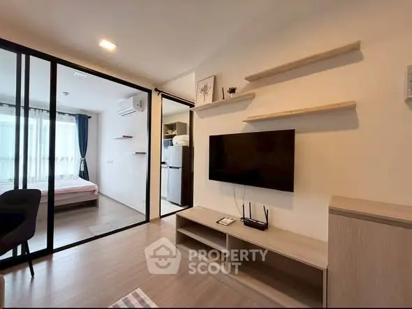 Modern apartment interior with open living room and bedroom, featuring sleek design and natural light.
