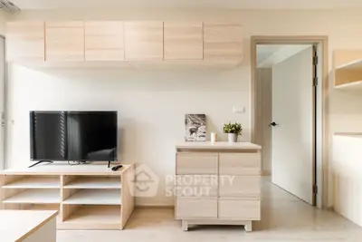 Modern minimalist living room with light wood furniture and TV setup.
